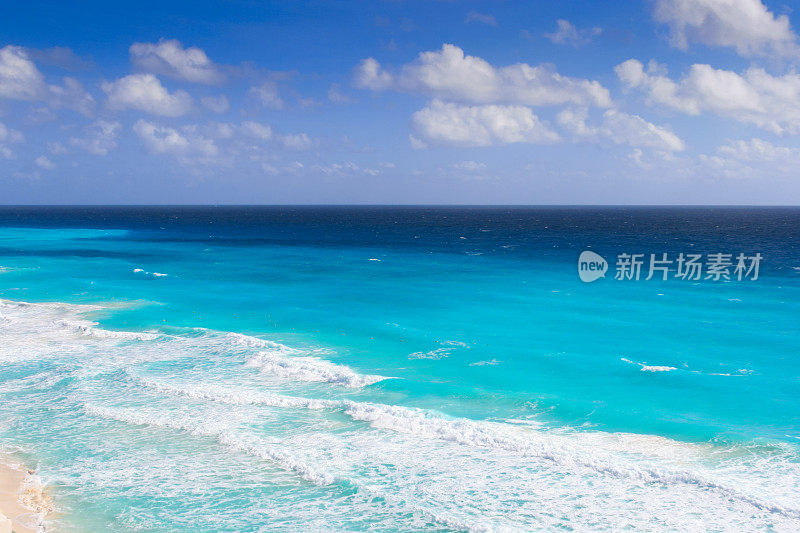 加勒比海与海浪打破海岸，蓝色和蓝绿色的水和蓝色的天空，坎昆，墨西哥。