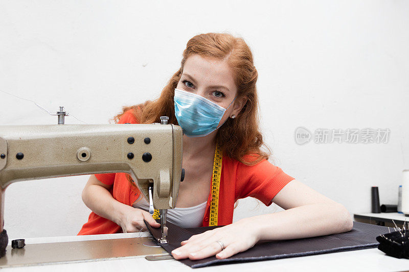 女裁缝企业家戴着防护面罩在她的工作室工作。