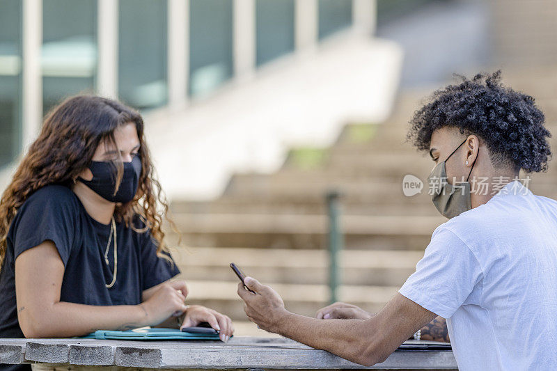 坐在校园里的学生戴着防护口罩