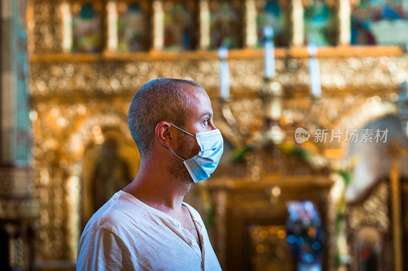 戴着防护面具在教堂祈祷的男子