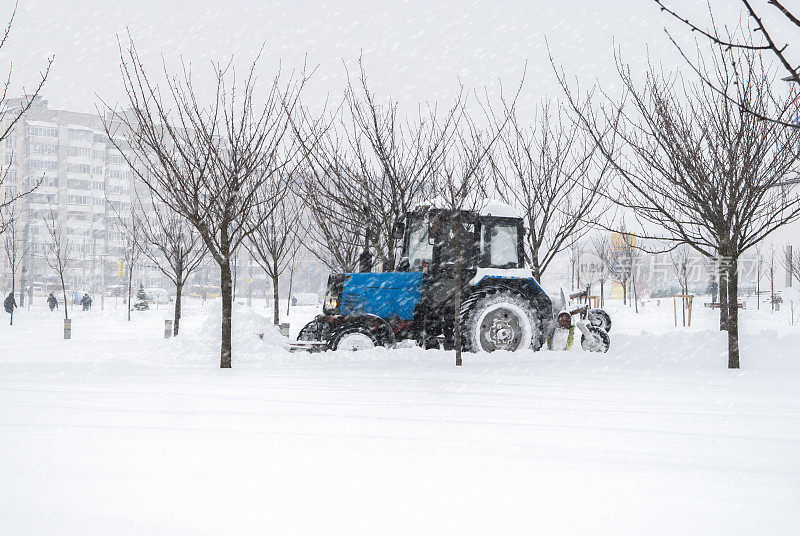 白雪覆盖的街道。扫雪机清除城市道路积雪。暴风雪，暴风雪交通。天气气候灾难。冬天的城市风光。雪后的雪堆