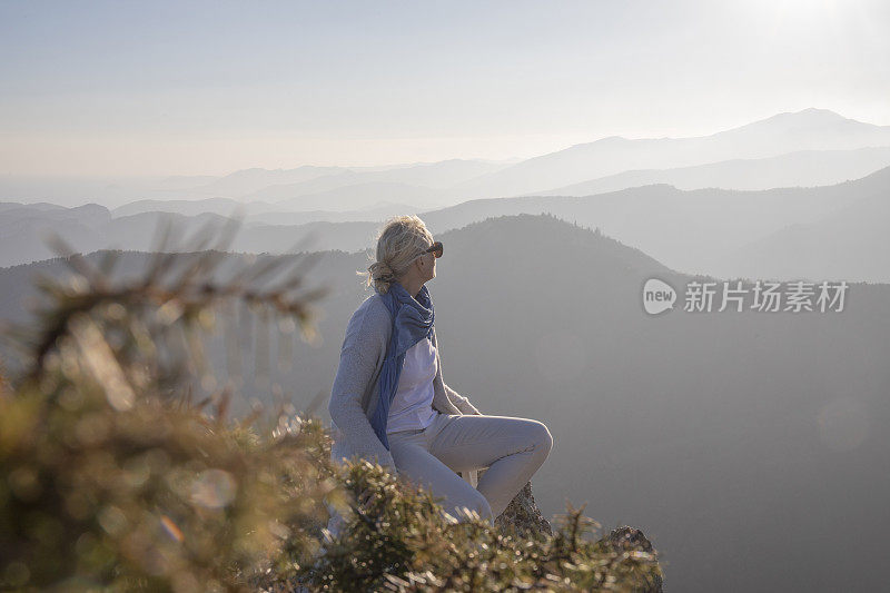 清晨，女徒步旅行者在阳光明媚的山脊上放松