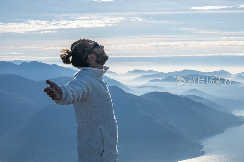 一个徒步旅行者双臂伸开站在山顶上