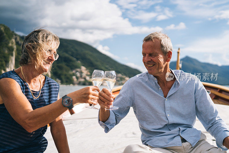 成年夫妇在卢加诺湖的帆船上享受香槟