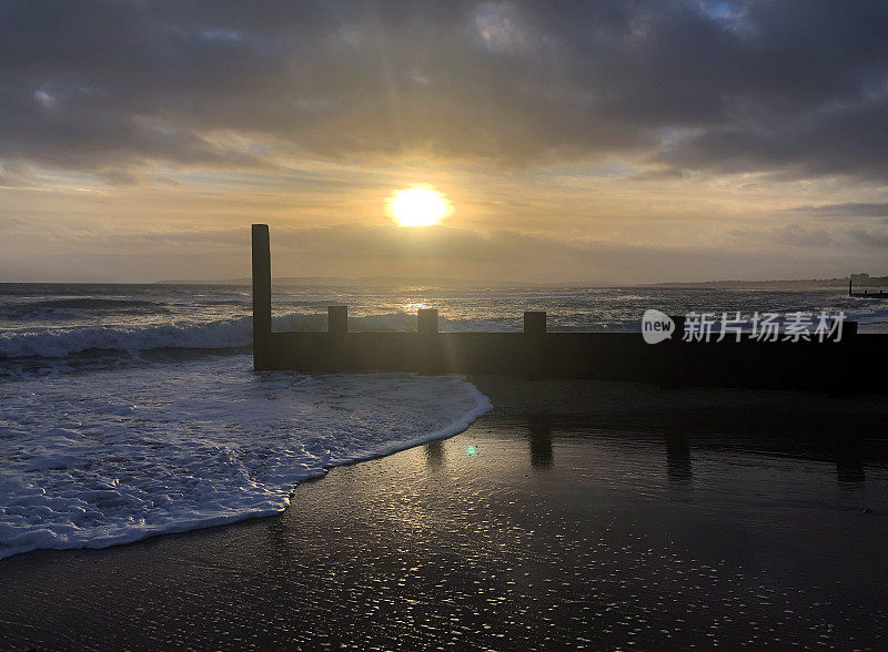 低太阳和剪影在冬季海滩景色，多塞特，英国