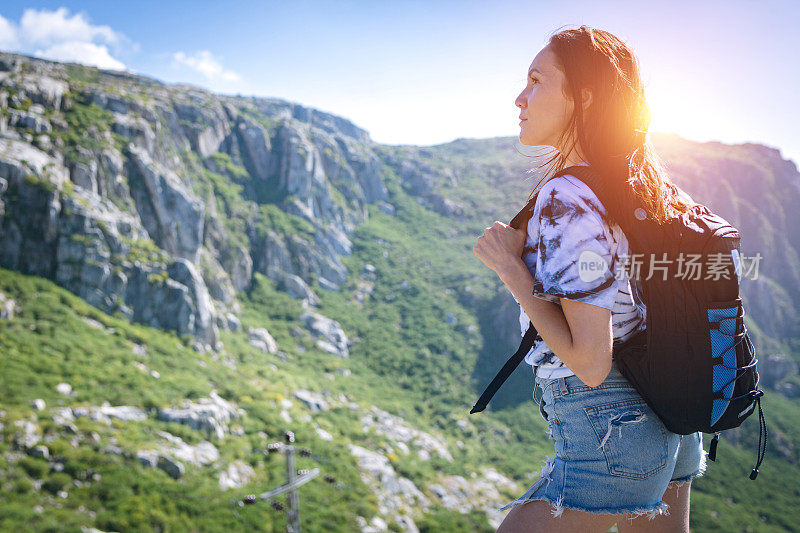 背着背包的年轻女子徒步旅行者在户外的山区旅行