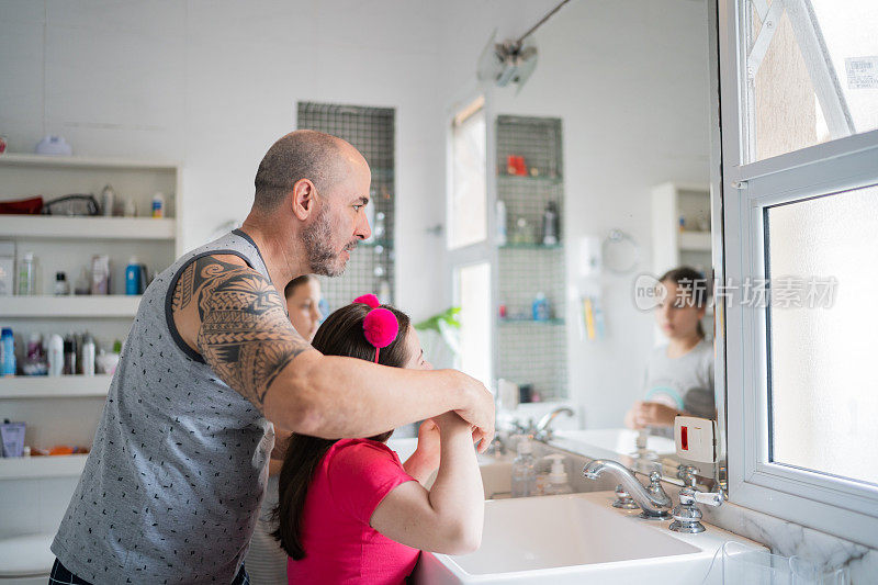 父亲帮助女儿刷牙早上在家-女孩与唐氏综合症