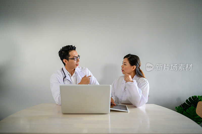 两个亚洲医生在会议期间使用笔记本电脑