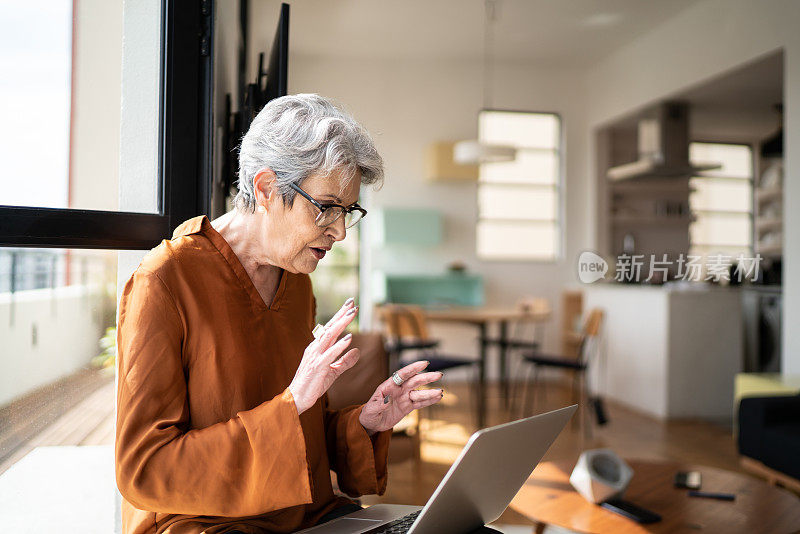 一位妇女正在家中用笔记本电脑进行虚拟商务通话