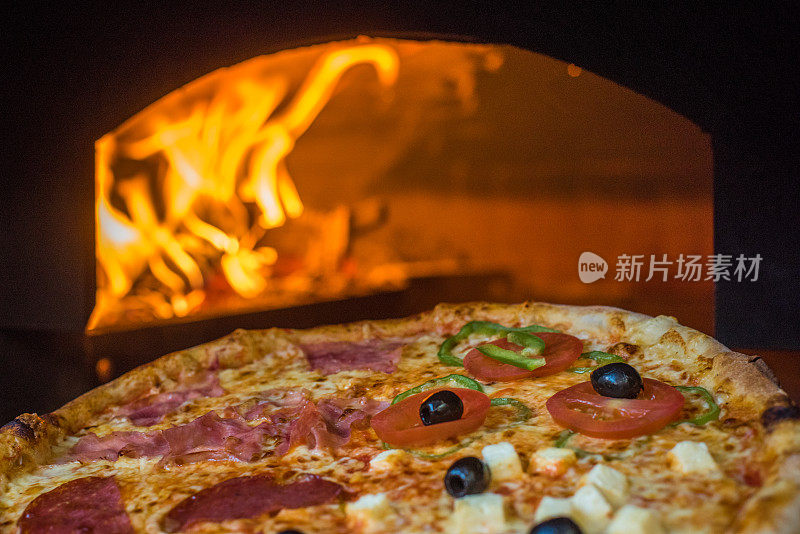 烤箱前的披萨，烘烤披萨的烤箱里面有燃烧的木头
