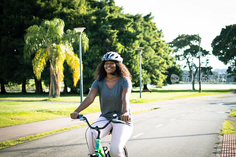 女孩戴着头盔骑着自行车在公园里愉快地骑着