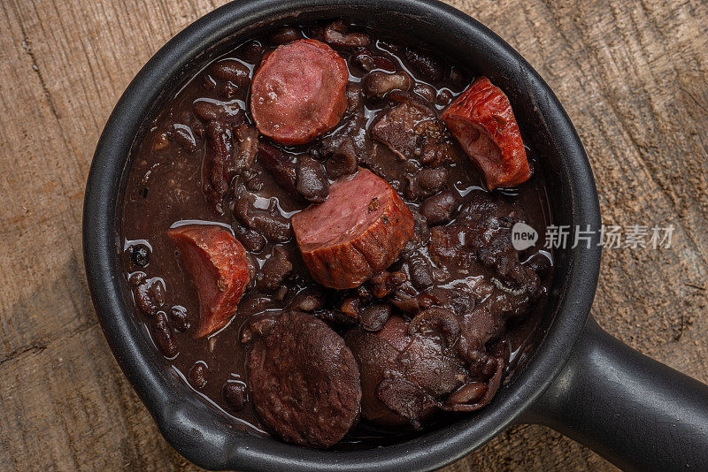 “FEIJOADA”装在陶土碗里，放在质朴的木桌上