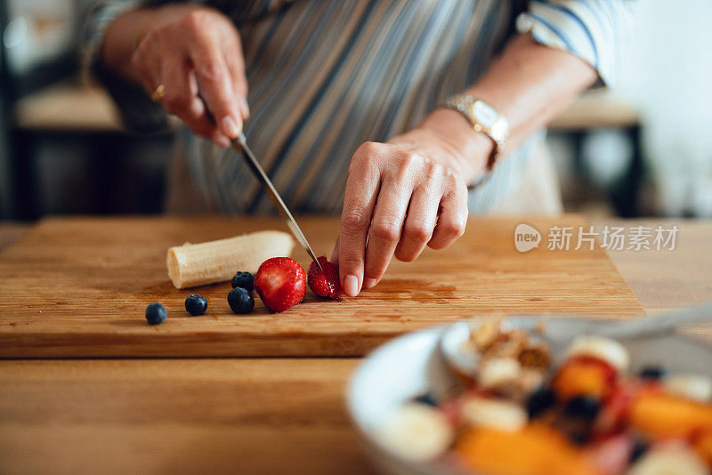 一名女子在家里的砧板上双手切水果的特写照片