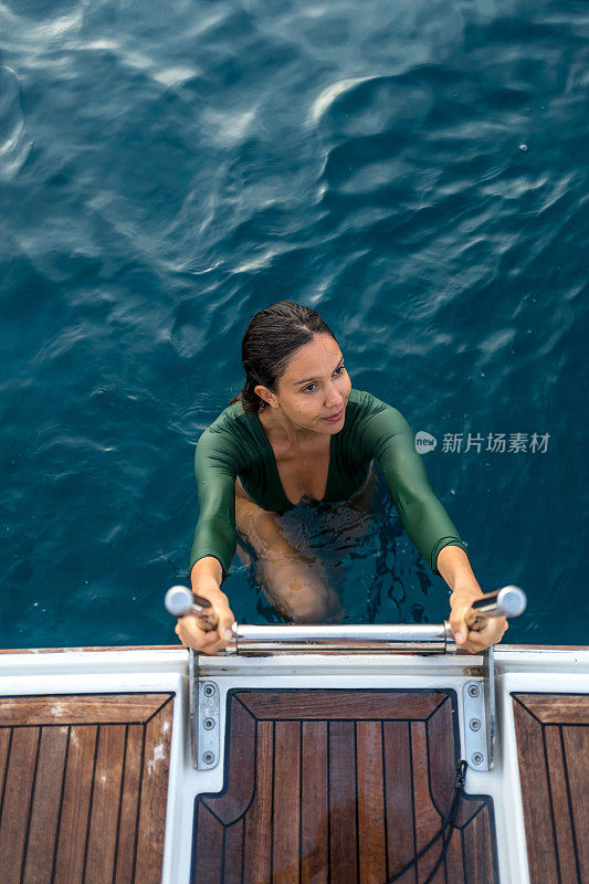 年轻女子在海上爬上梯子上船