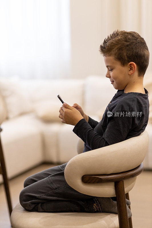 男孩坐在椅子上玩手机