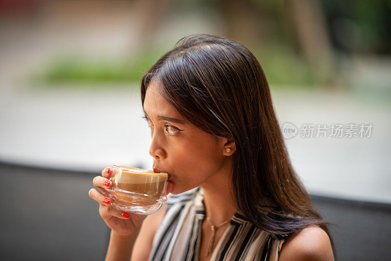 生活中的小奢侈品。特写美丽的亚洲妇女喝卡布奇诺购物