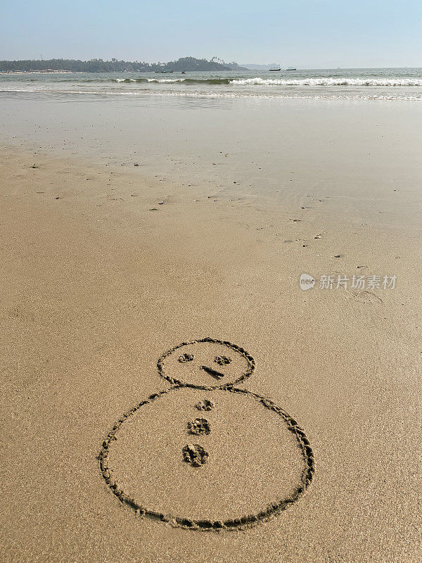 图像的雪人木棍鼻子画在沙滩上的阳光沙滩边的水，海洋背景，重点在前景，复制空间，圣诞节在南半球的概念