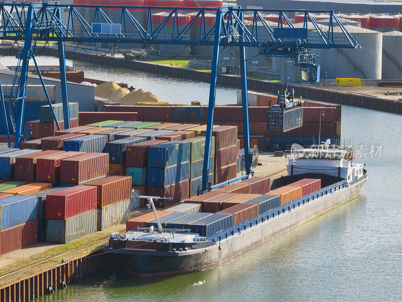 河岸边的集装箱码头，有各种货运集装箱和龙门吊