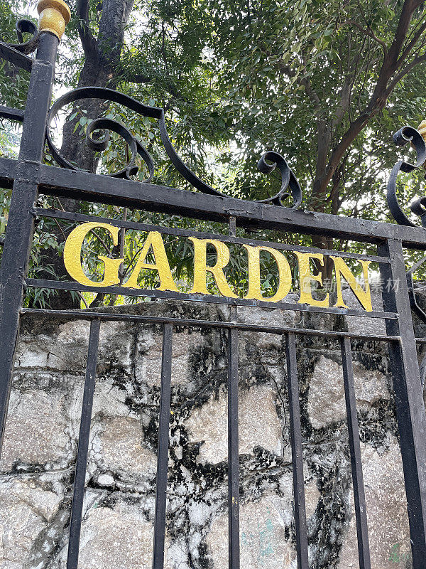 黑色锻铁门上的金色标志的特写图像，金属门上的“花园”标志，重点在前景