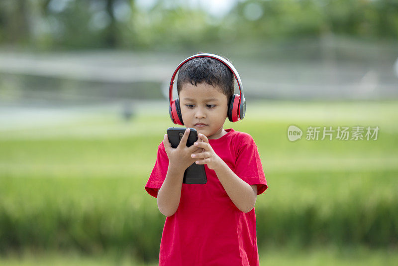 蹒跚学步的男孩用耳机听音乐