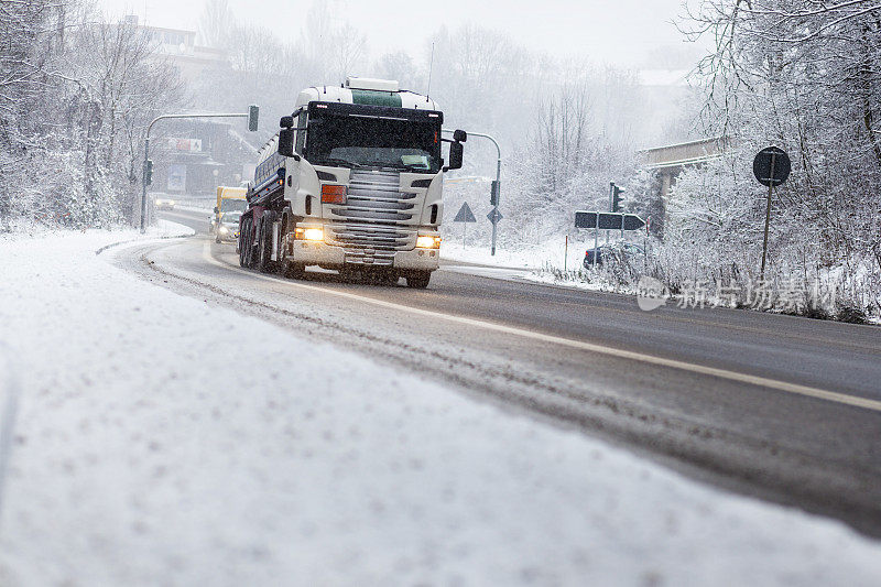 道路上的汽车和卡车在冬天的降雪中缓慢行驶