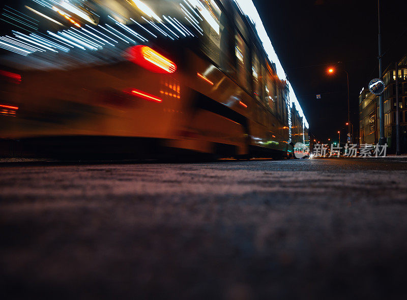 灯火通明的公共汽车在夜晚的城市街道上快速行驶