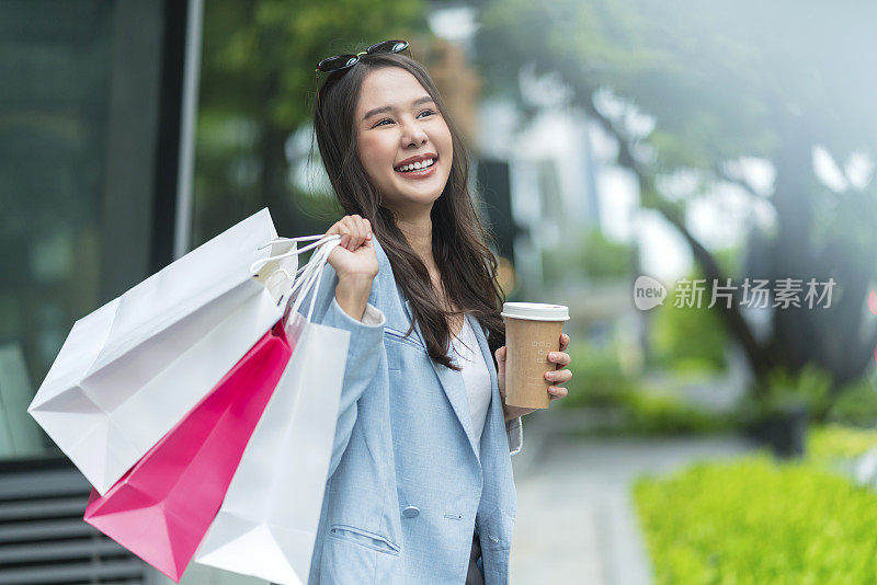幸福亚洲女人女人手拿购物纸袋在奥特莱斯商店中心购物中心散步和购物与快乐无忧无虑的周末，享受在购物。消费主义，购物，生活理念