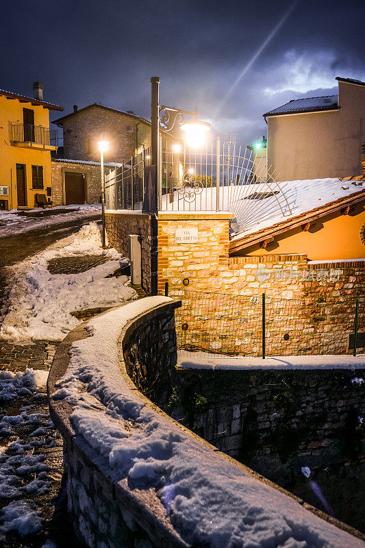 翁布里亚(Umbria)一个中世纪村庄的积雪小巷，夜晚的冬日氛围