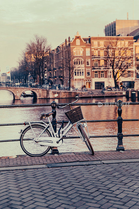 优雅的城市自行车停放在阿姆斯特丹运河，冬季日落
