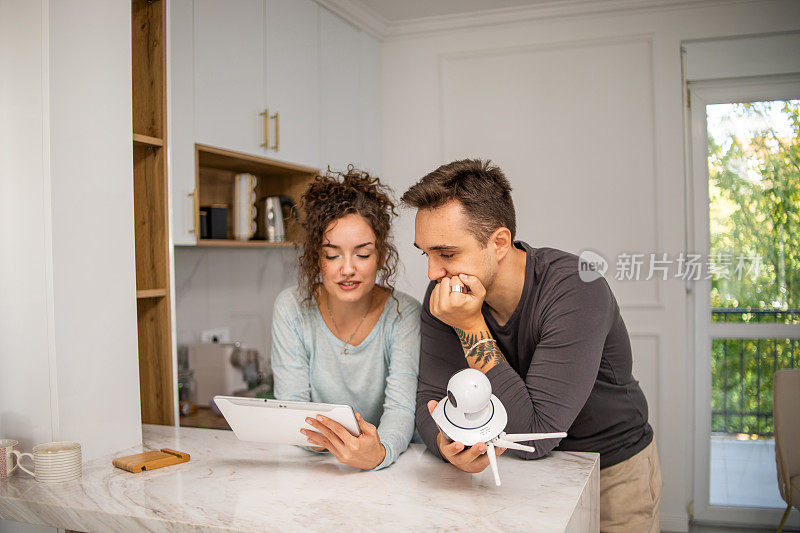 一对年轻夫妇，一男一女，正在他们的公寓里安装家庭监控摄像头