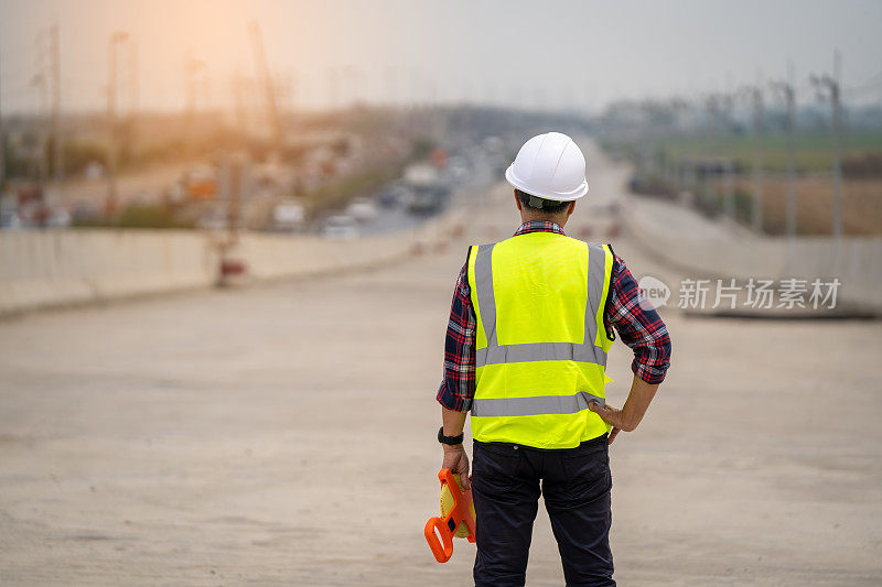 男工程师在道路施工过程中检验和测量标准混凝土梁。在建筑工地