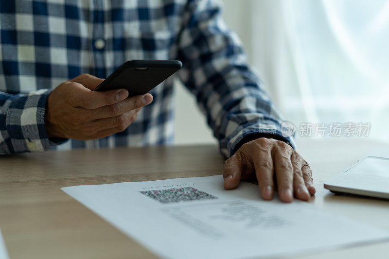 一名男子用智能手机扫描发票上的二维码进行收费。金融科技的概念，网上还款。