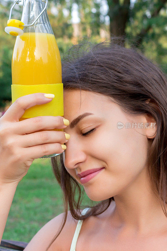 在炎热的夏日里，年轻美丽的女子试图用一瓶冷果汁来提神