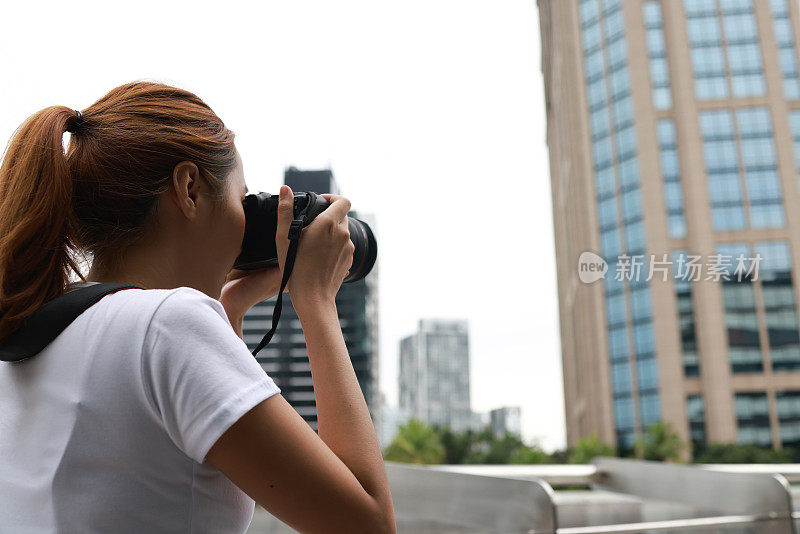 亚洲女性游客或学生在城市街道上用数码相机拍照的肖像。度假旅游概念。一名年轻女子在高楼上拍摄曼谷城市的照片。旅游及旅游概念