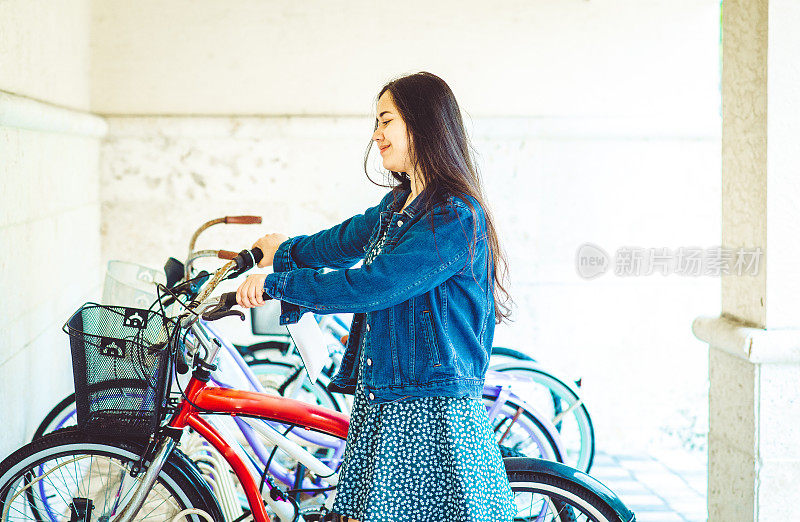 年轻的亚洲女大学生在校园里骑自行车