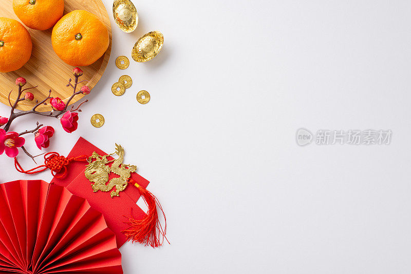 春节喜庆的概念。传统硬币的俯视图，装饰风扇，盘子与橘子，金色的sycee，复杂的剪纸在喜庆的白色背景和空间的问候