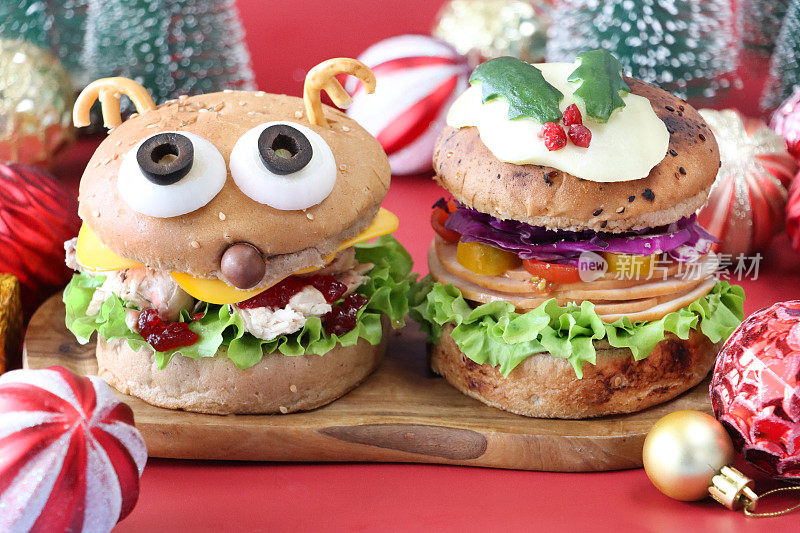 圣诞布丁和驯鹿设计三明治在木制砧板上的特写图像，周围是塑料冷杉树和装饰物，红色背景，重点在前景