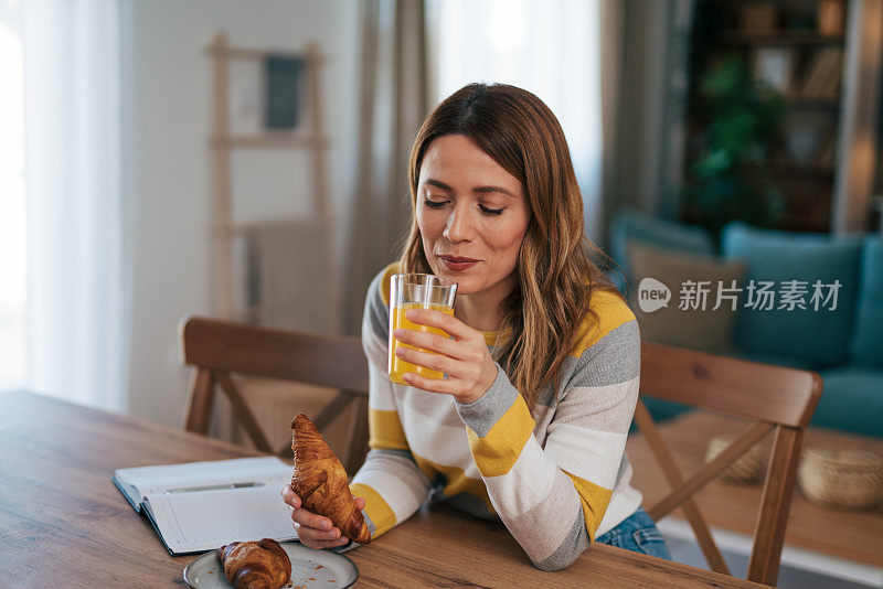 一位年轻女子在家，坐在餐厅的椅子上写笔记