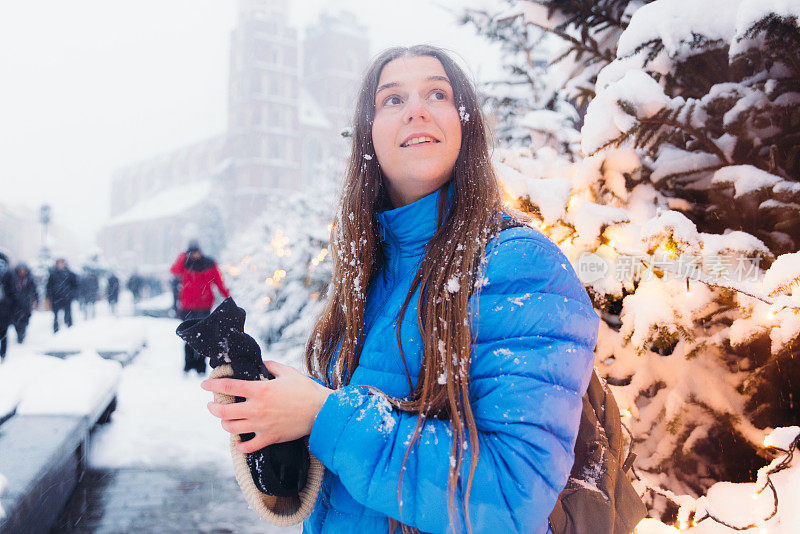 快乐的女人背着背包，在克拉科夫思考下雪的圣诞节