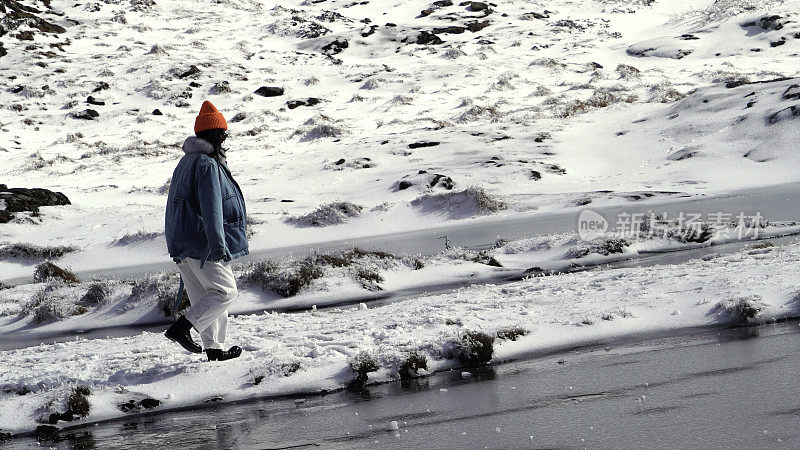 一个女人在寒冷的天气里穿行于白雪覆盖的山林之中