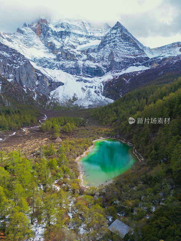 中国亚丁自然保护区无人机鸟瞰图。白雪皑皑的陈若芝风景如画，四周环绕着常绿的树木和湖泊