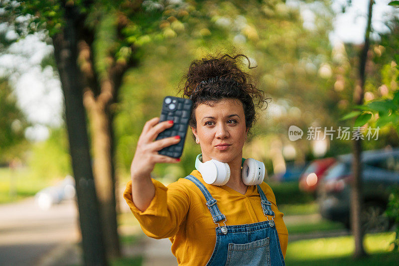 一位成年妇女站在街上，正在进行视频通话。