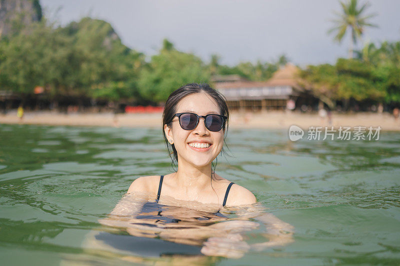 享受热带海洋生活的女人，在夕阳的时刻，在翠绿的热带海洋中嬉戏