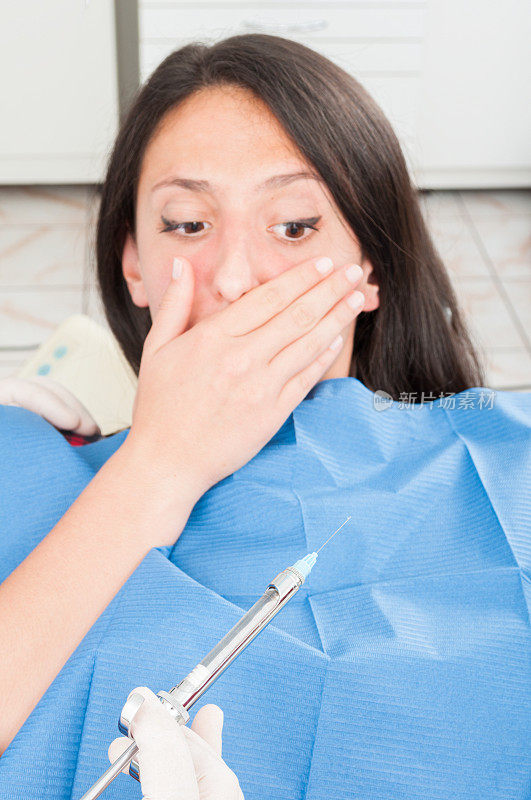 坐在牙医椅上的女士害怕麻醉针