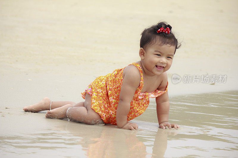 亚洲婴儿在沙滩上微笑
