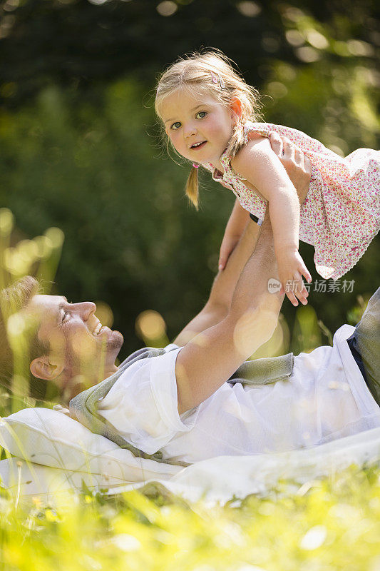 父亲躺在花园里，把女儿举到空中