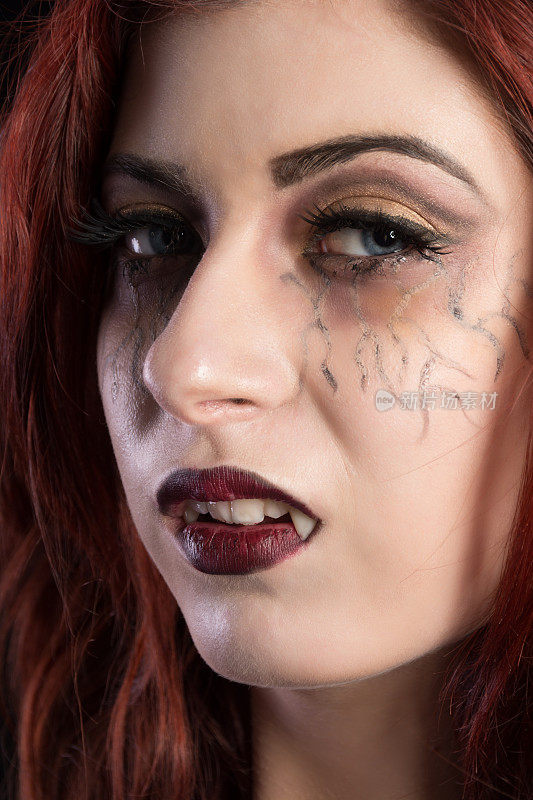 恼怒的女吸血鬼，垂直特写，红发，尖牙显示。