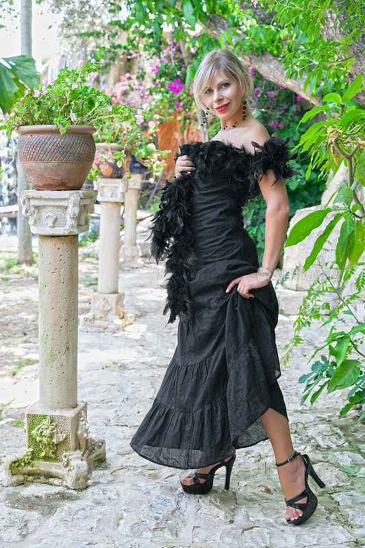 身着黑色晚礼服的优雅女子站在花园里