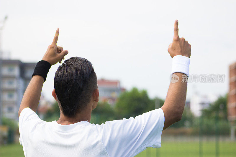 欢呼的年轻足球运动员用手做箭头手势