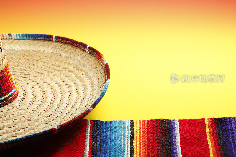 宽边帽和墨西哥毛毯在明亮的黄色背景